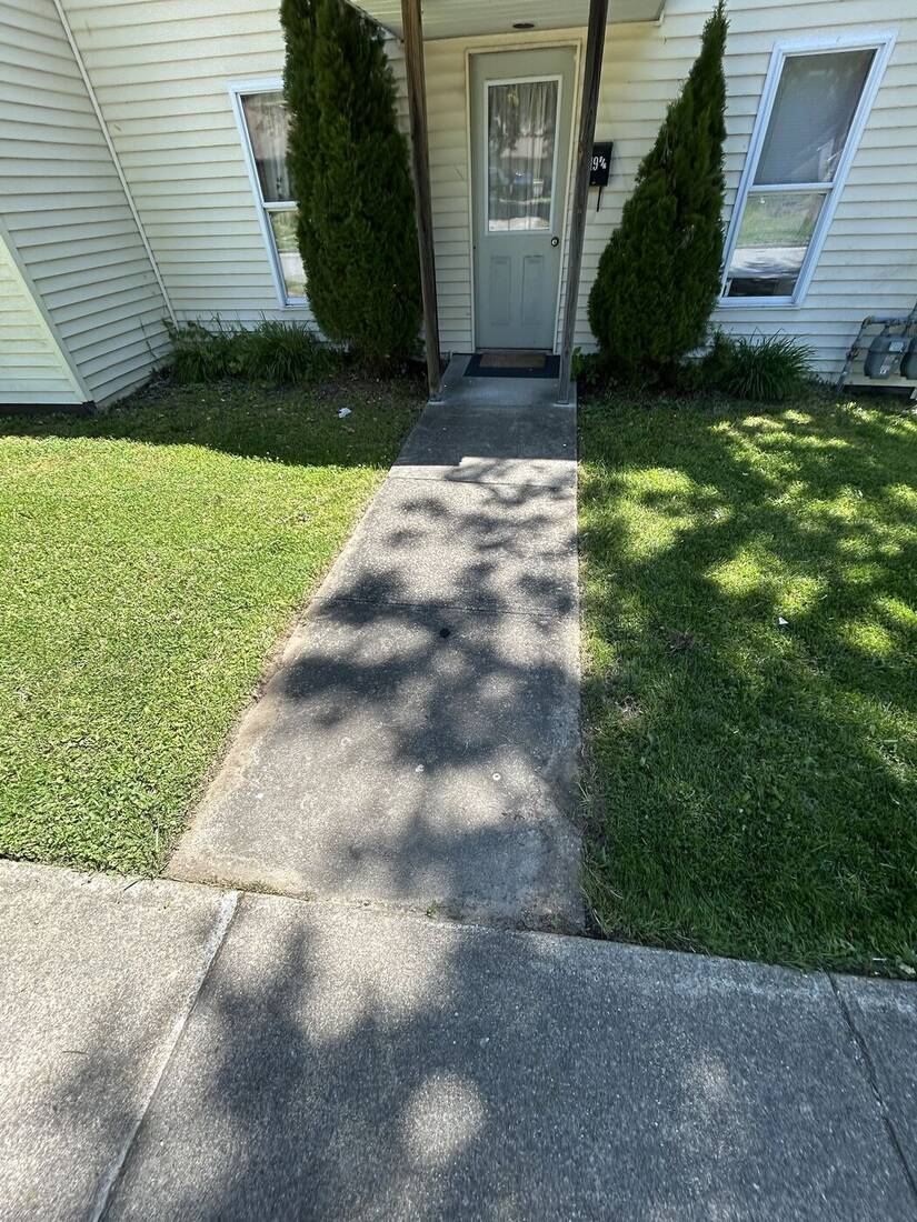 Front entry beds with arborvitae beside an edged walkway